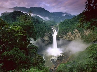 Foto de referencia: cascada de gran caída entre montañas cubiertas de selva y neblina.